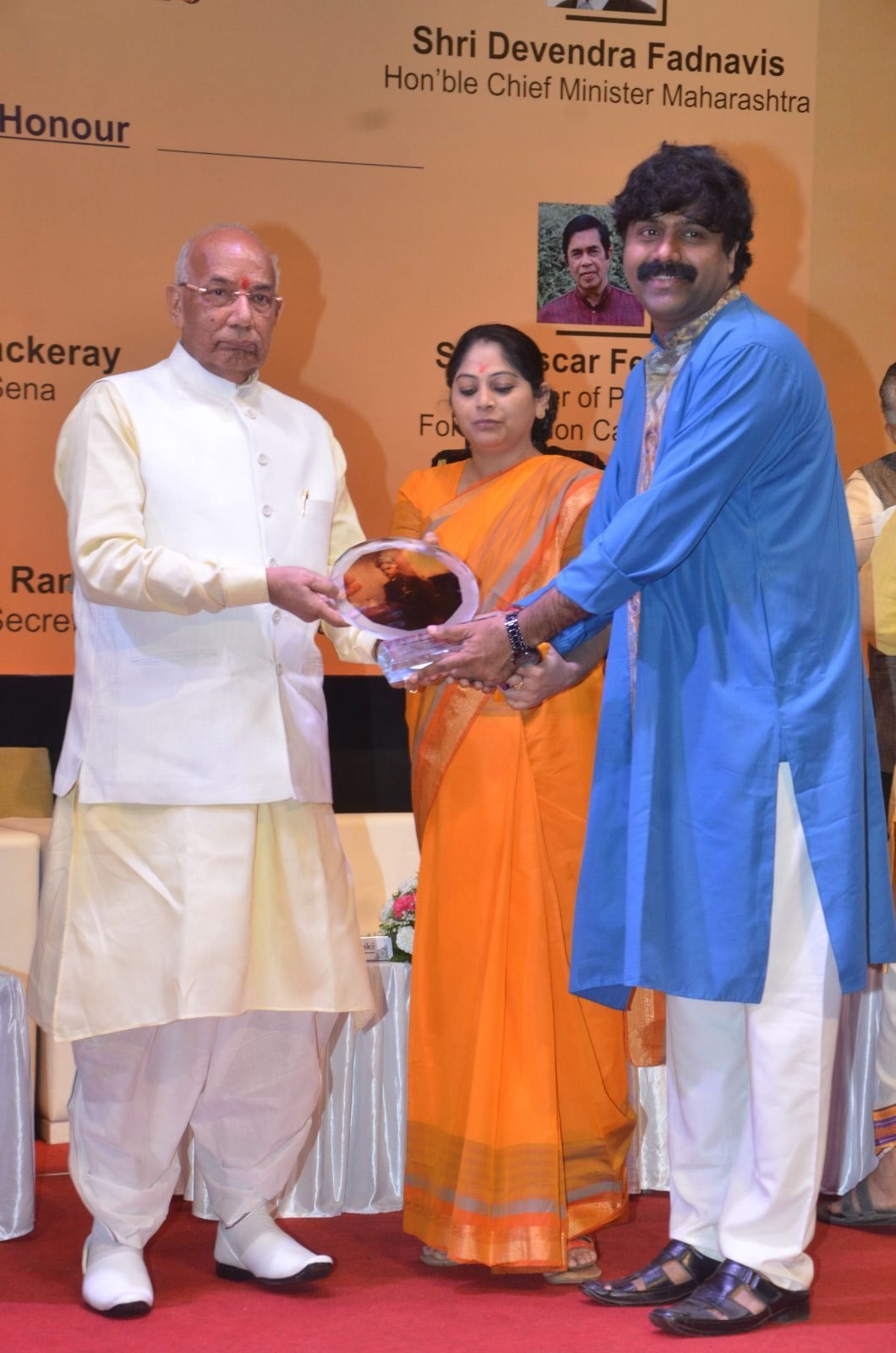 An artist receiving a memento on stage at Chitranjali