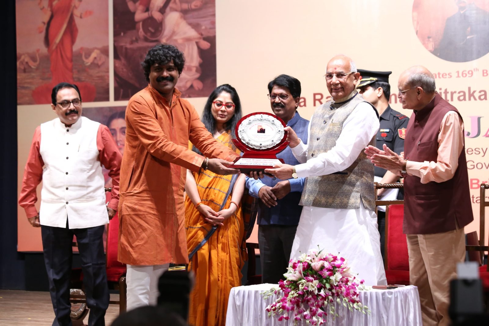 An artist in an orange kurta receiving his award at Chitranjali 2017